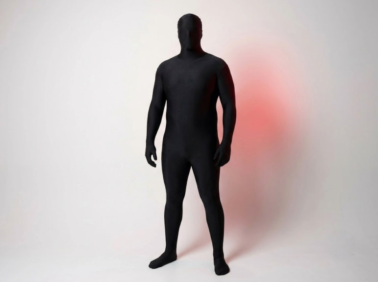 Tall broad-built man wearing a plain black full-body morphsuit that fits comfortably without straining.
