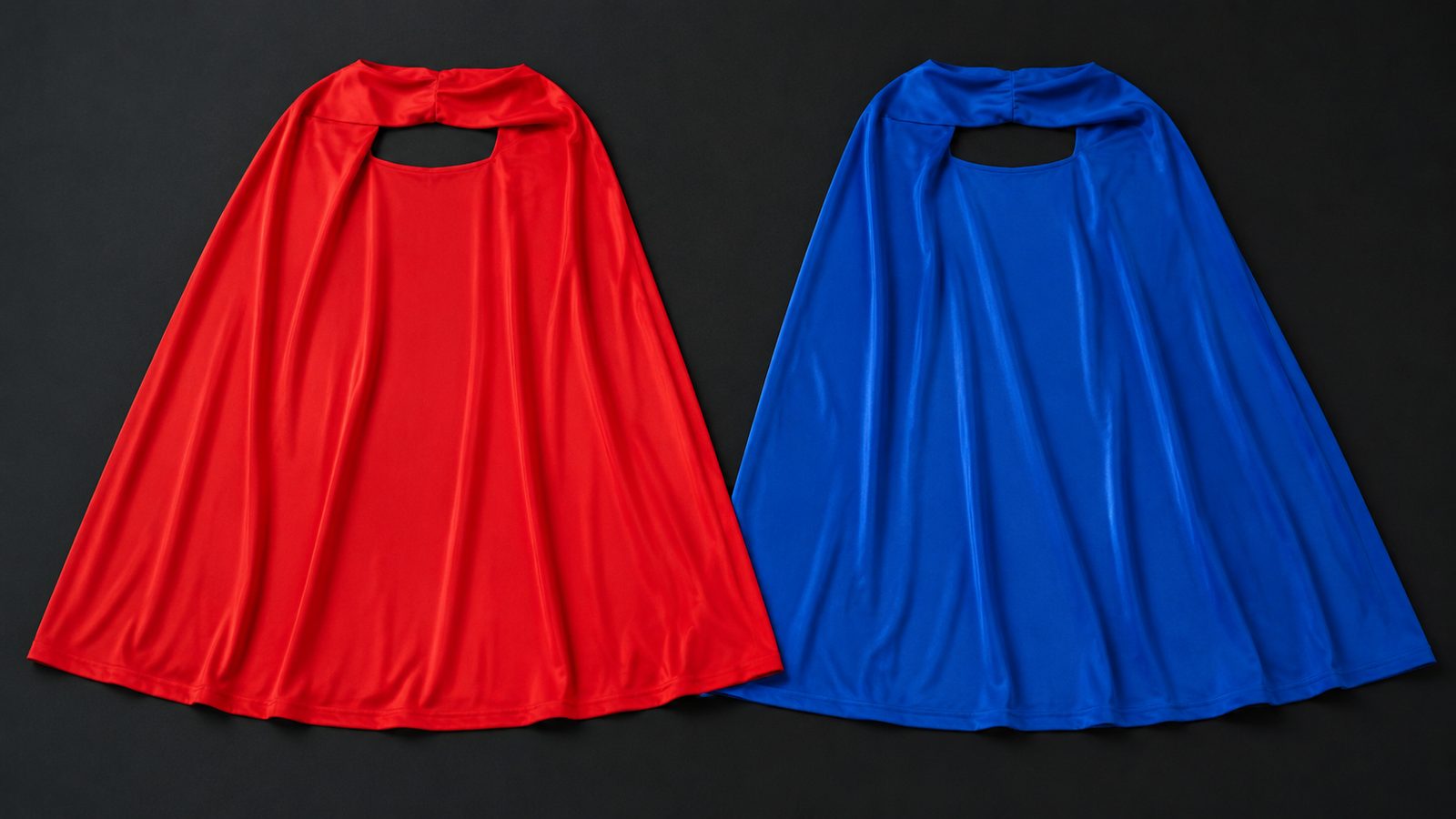 Close-up detail of the red and blue superhero capes laid out together, showing the plain polyester fabric and simple one-size cut