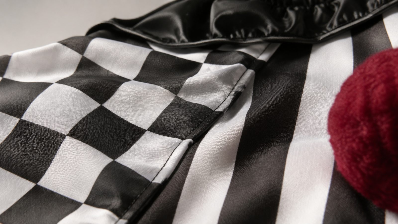 Close-up of distressed black and white harlequin-print costume fabric with reinforced stitching along a seam
