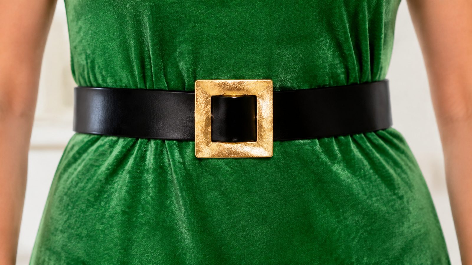 Close-up of a green costume dress waist with a black belt and gold buckle, showing the adjustable fit at the waistband