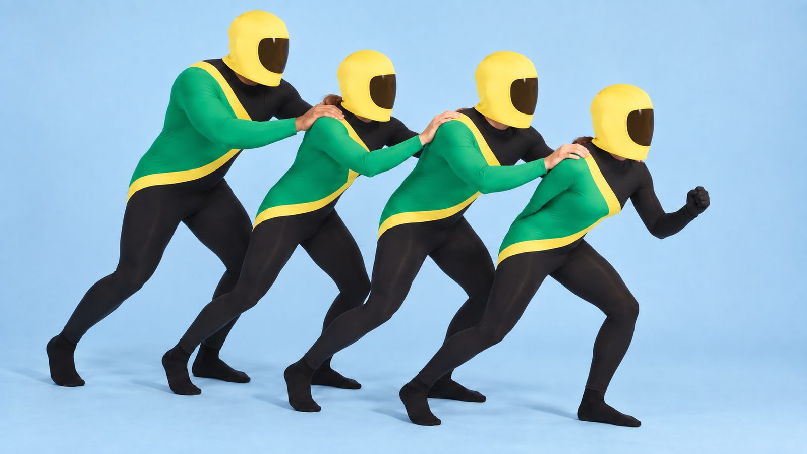 Four friends in matching black, green and gold bobsleigh team Morphsuits with yellow helmet hoods, lined up in single file