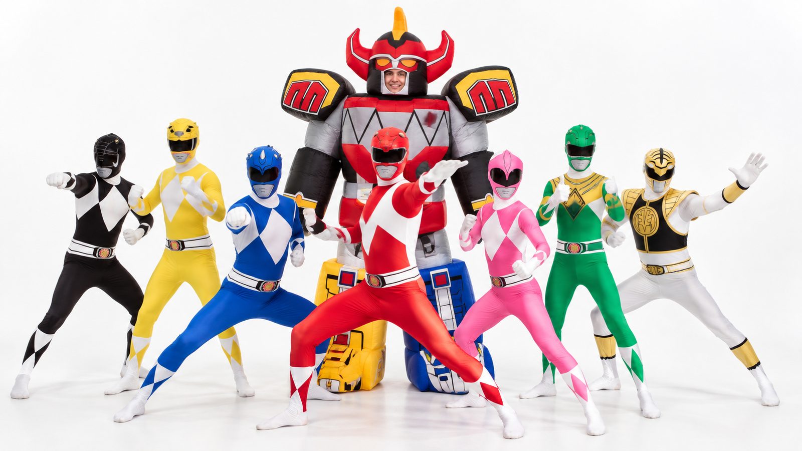 Seven friends in red, blue, yellow, pink, black, green and white Power Rangers Morphsuits standing with a friend in a giant inflatable Megazord costume