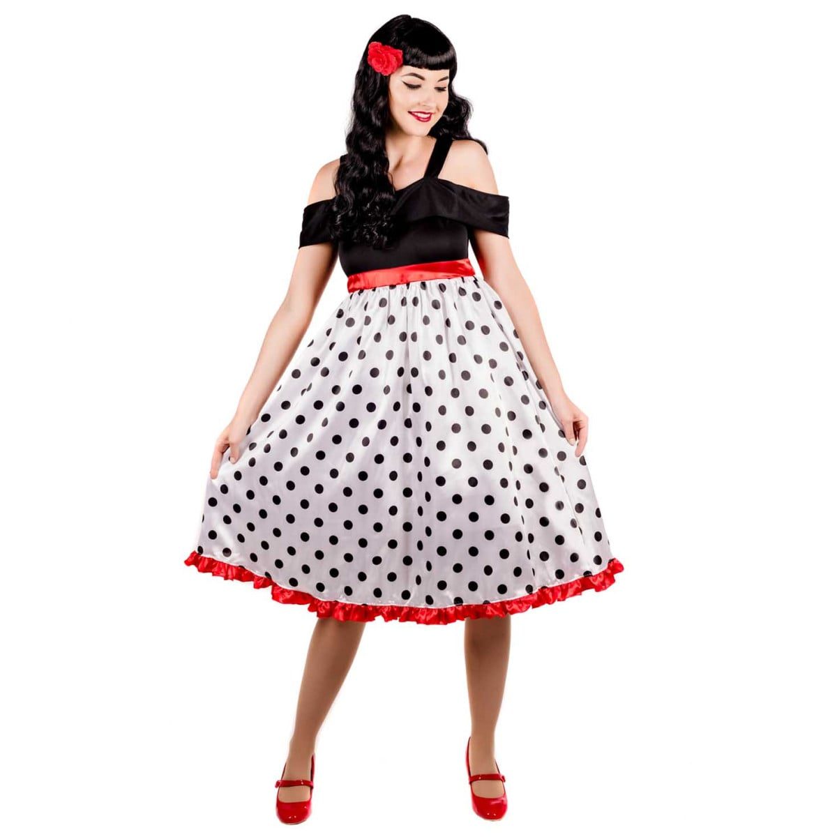 Woman wearing a multi-coloured polka dot dress with a red ruffled hem, with a matching red flower hairclip