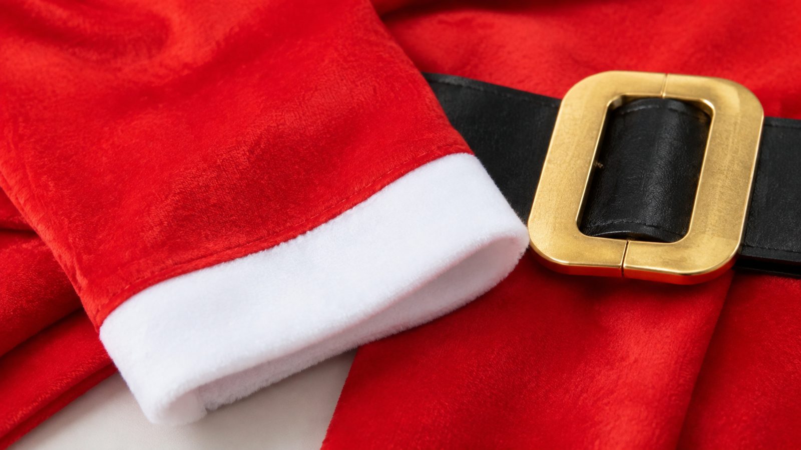Close-up detail of the Womens Santa Costume showing the velvet-textured red fabric, white faux fur trim, and gold belt buckle