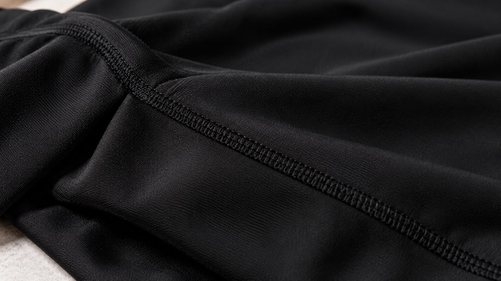 Close-up detail of the Kids Black Morphsuit showing the smooth black spandex fabric and a seam line, no mesh visible