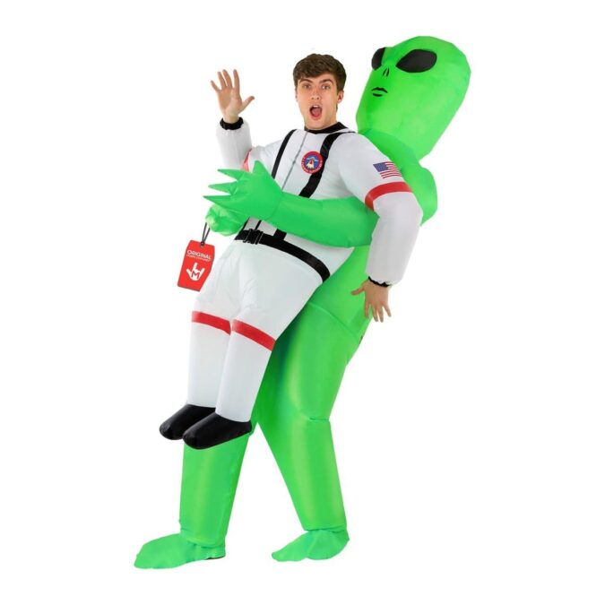 Inflatable Alien with Astronaut Costume Pick Me Up: a bright green inflatable alien carrying a man dressed in a white astronaut suit with black straps and mission patches, his own head and arms free and his fake legs in black boots