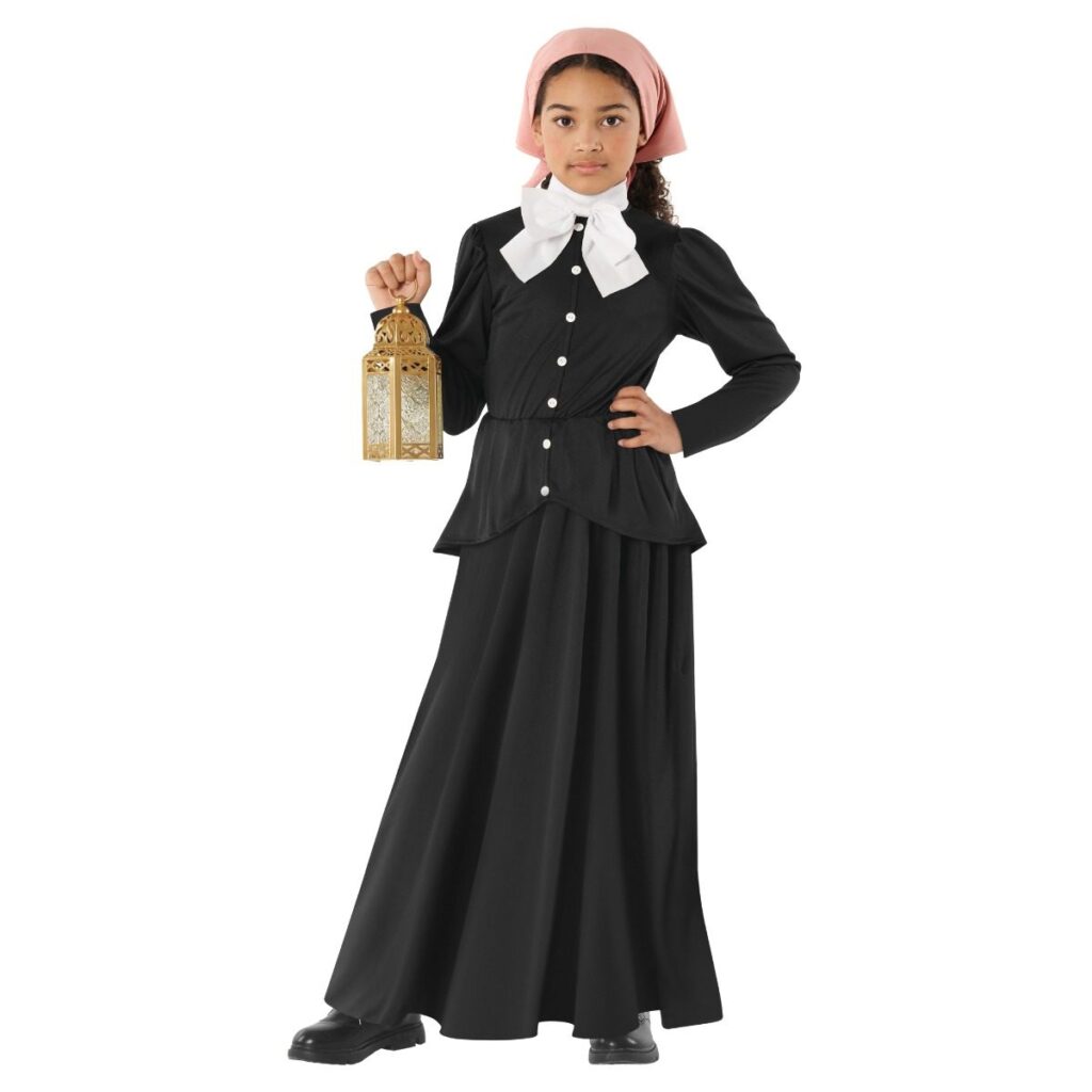 Girl in a long black period dress with a peplum waist, white bow collar and pink headscarf, holding a lantern