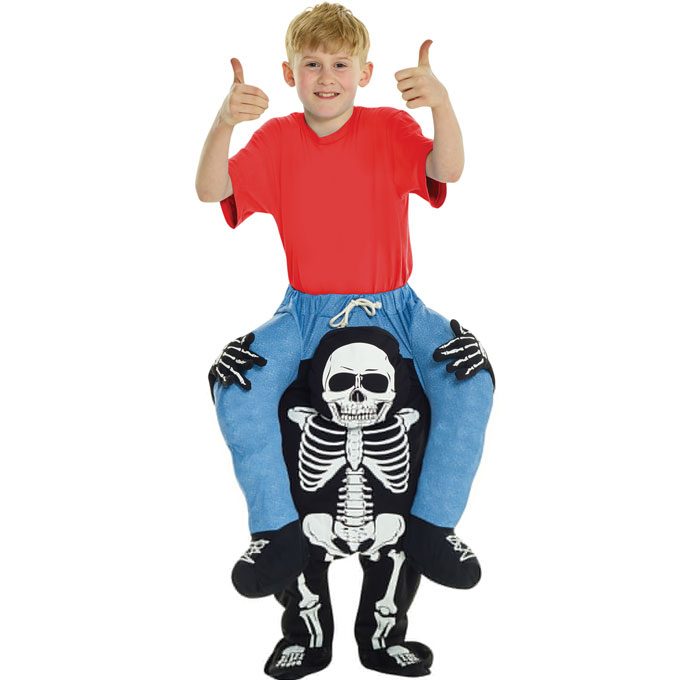 Child in a red t-shirt wearing a skeleton piggyback costume, so it looks like a cartoon skeleton in blue trousers is carrying them, its bony hands gripping their sides and its stuffed legs and shoes hanging down