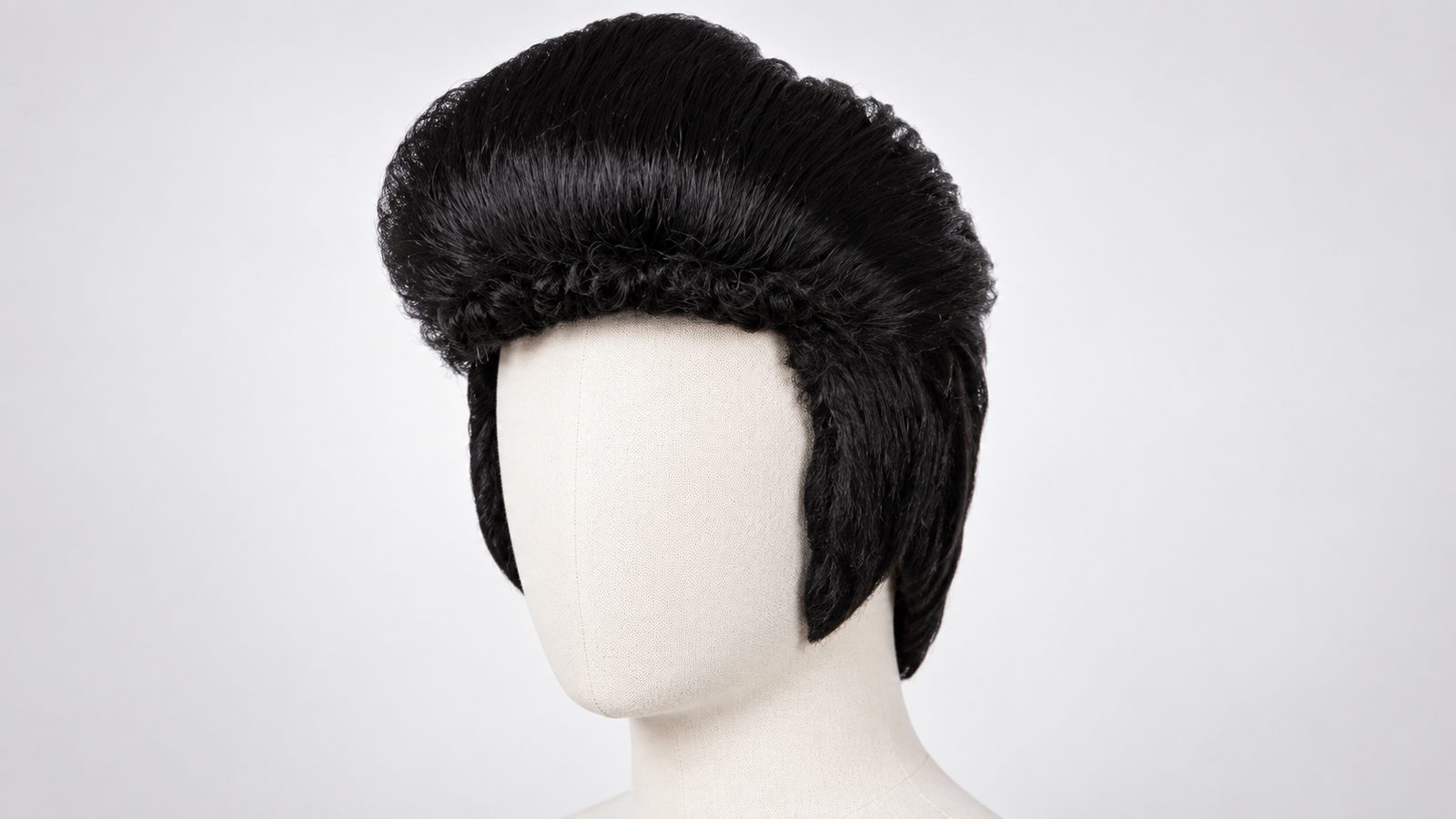 Close-up of a black quiff-style wig with sideburns on a wig stand against a plain background