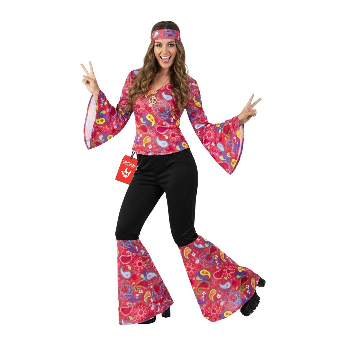 Woman in a pink paisley top with wide bell sleeves, black high-waisted pants flaring into paisley panels below the knee, a matching headband, and a peace medallion, making peace signs, with platform boots